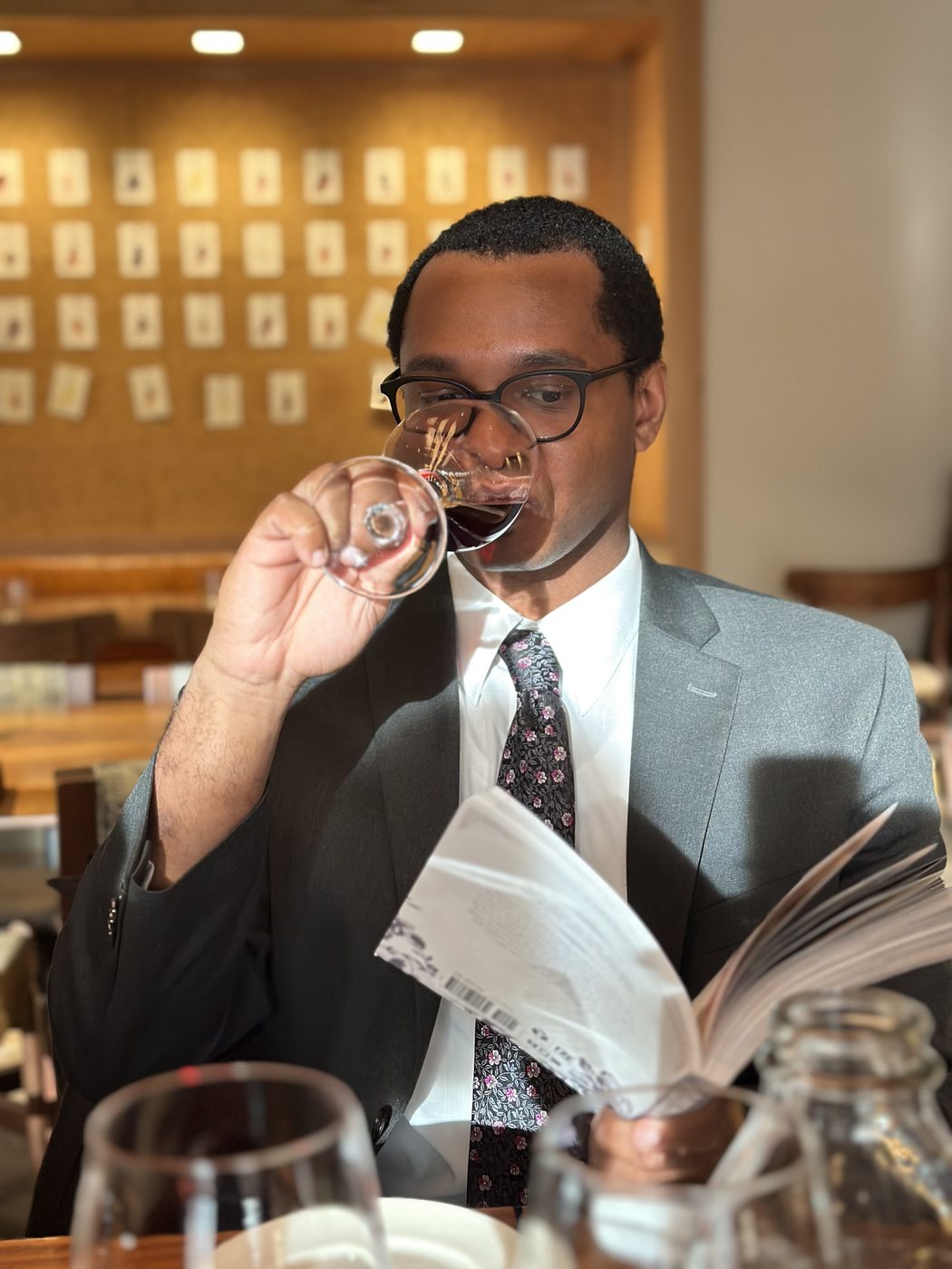 A guest tasting a pour of red wine while reading the wine list